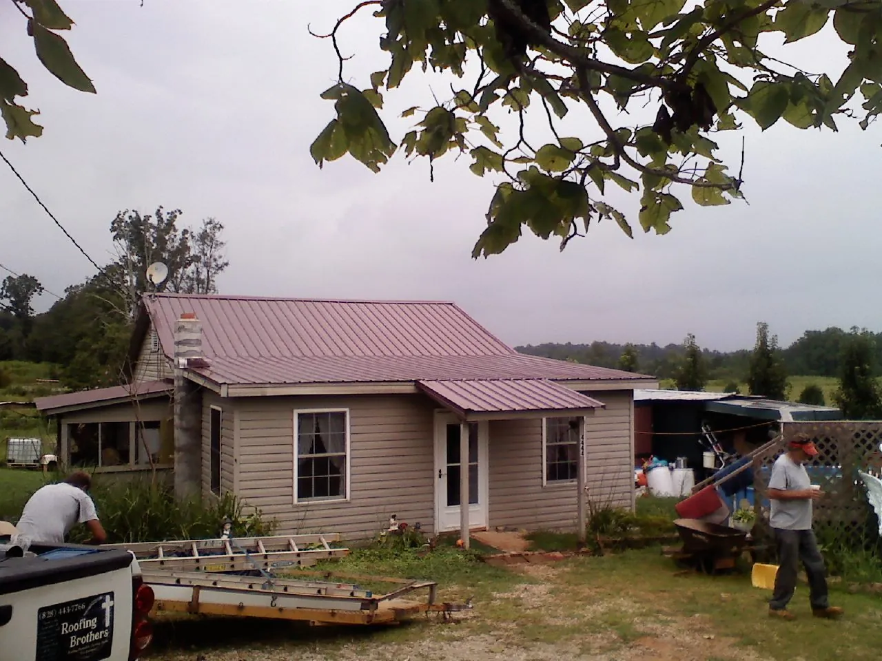 Crew finishing a mauve metal roof on a small farmhouse in Gainesboro