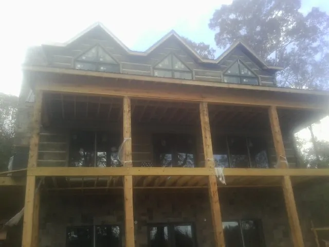 Dormers and porch framing on a large log home under construction — Roof Coating work by our crew in Gainesboro