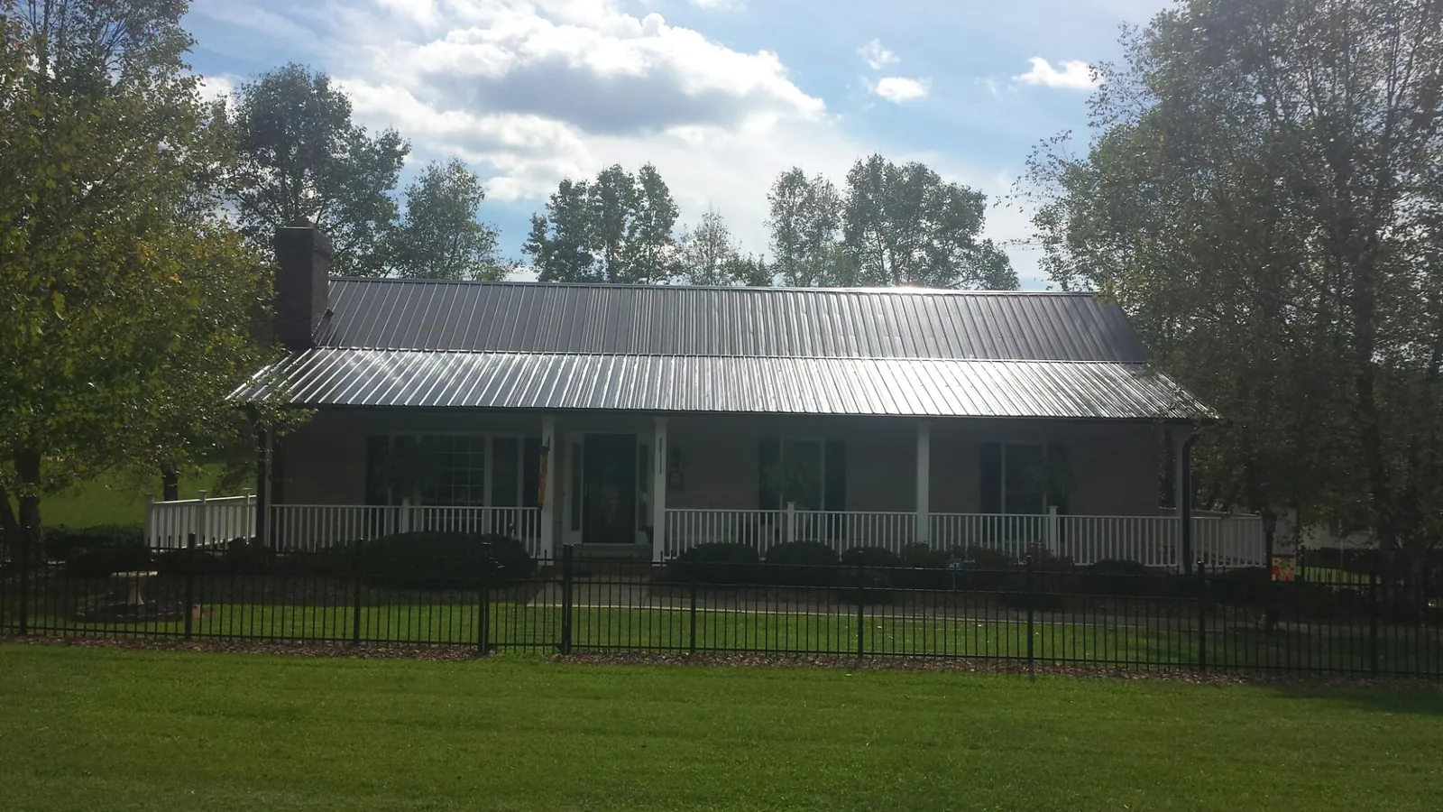 Gray metal roof on a brick ranch with a full width front porch — Gutter Guard Installation work by our crew in Gainesboro