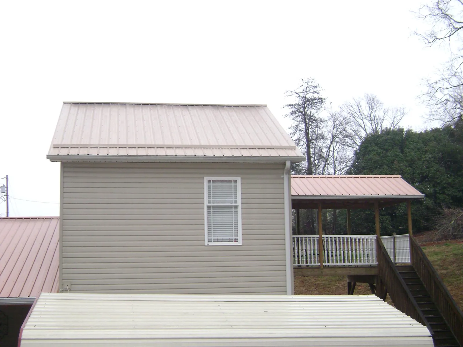 Tan metal roofs on a two story addition and attached porch, from a Roof Replacement job in Gainesboro