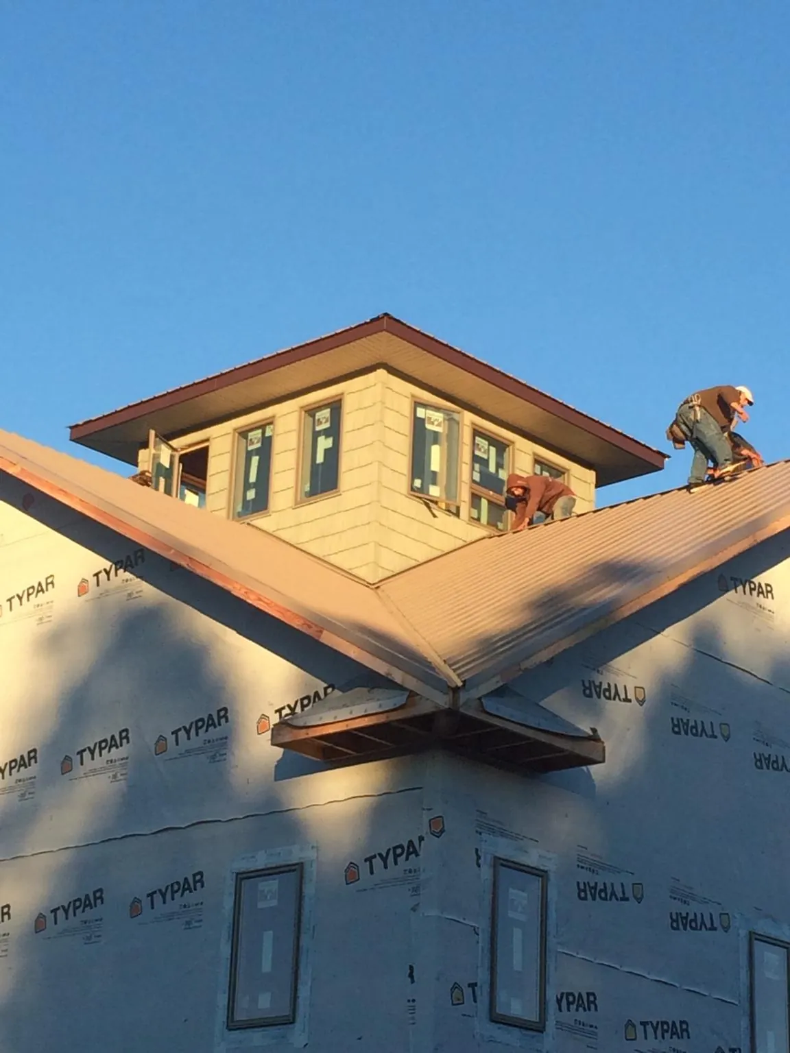 Roofers working around a rooftop cupola on a new metal roof at sunset — Roof Waterproofing in Gainesboro by Roofing Brothers
